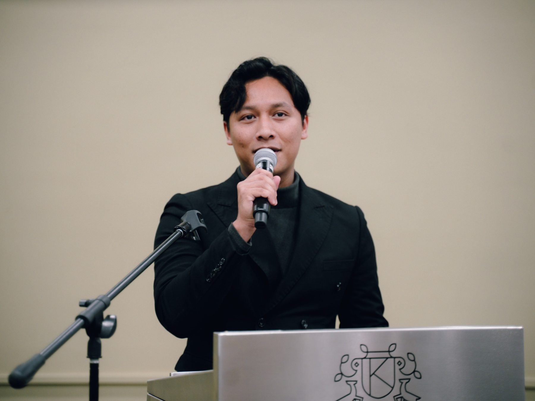 Irfan speaking at a lectern in a black suit